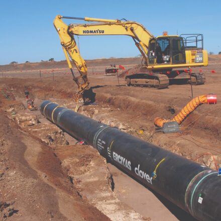excavator laying pipe in a trench