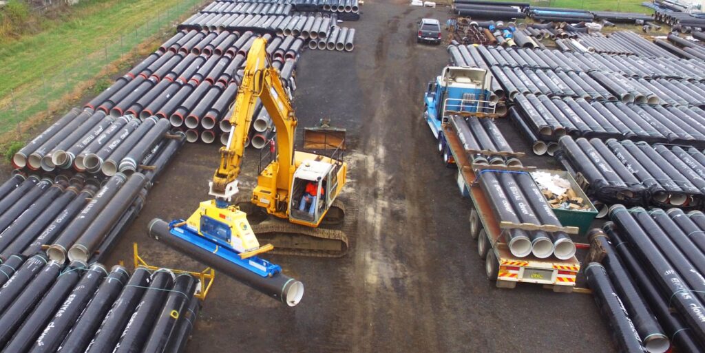 excavators moving pipe in a storage yard