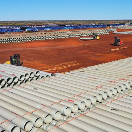 Aerial shot of rows of stacked GRP pipe in orange dirt.