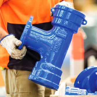 Warehouse worker holding a large Ductile iron fitting