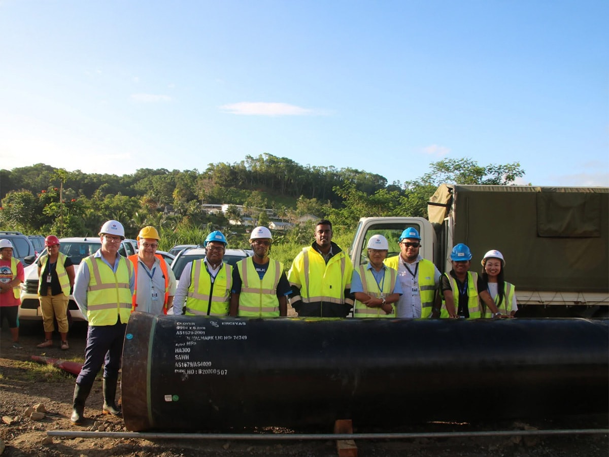Rewa team in high-vis standing behind a Clover pipe. 
